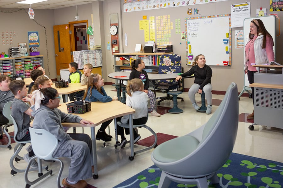 Teacher and students trying out new classroom furniture